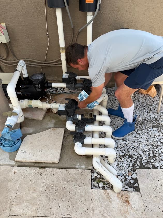 Technician inspecting pool plumbing and unions for suction- and pressure-side leaks