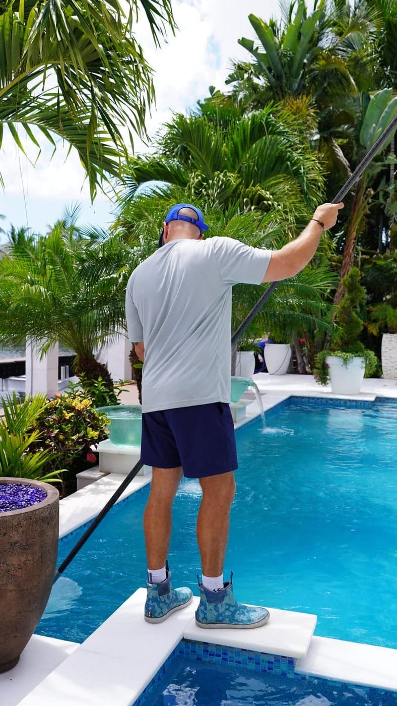 Florida's Best Pools technician skimming a pool