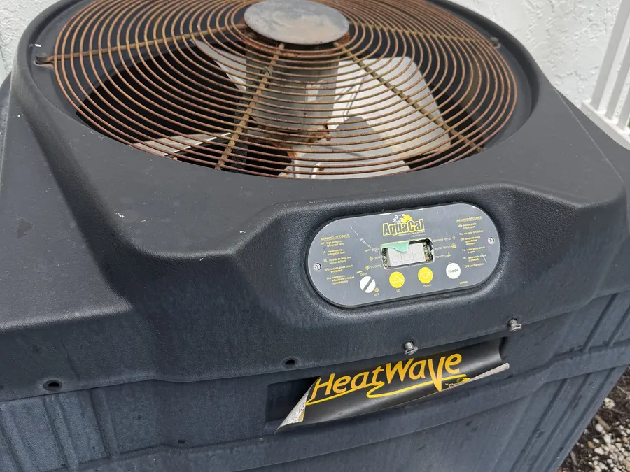 A corroded, end-of-life pool heater on a Boca Raton equipment pad — etched heat exchanger and rusted cabinet, the kind of unit that's past repair and due for replacement