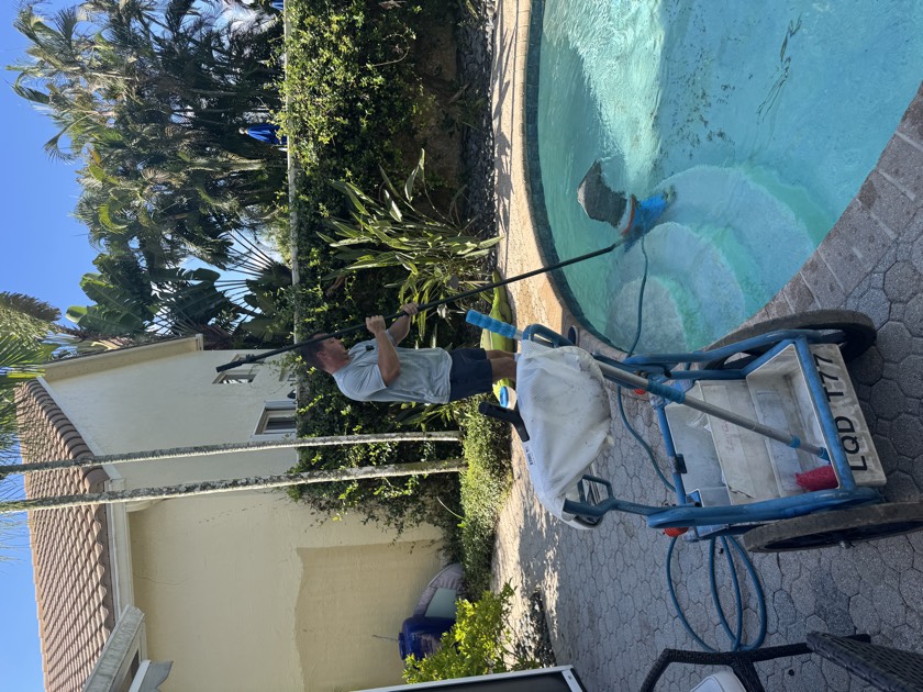 Florida's Best Pools technician vacuuming a South Florida pool floor during a weekly maintenance visit