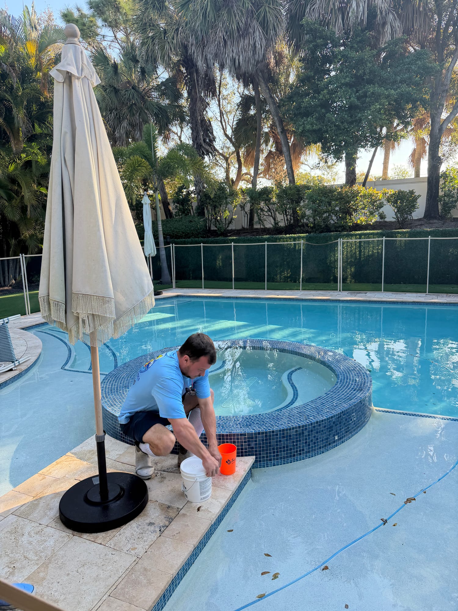 Florida's Best Pools technician servicing the spa side of a Delray Beach country-club pool — attached spas, tanning shelves, and water features need separate chemistry attention every visit